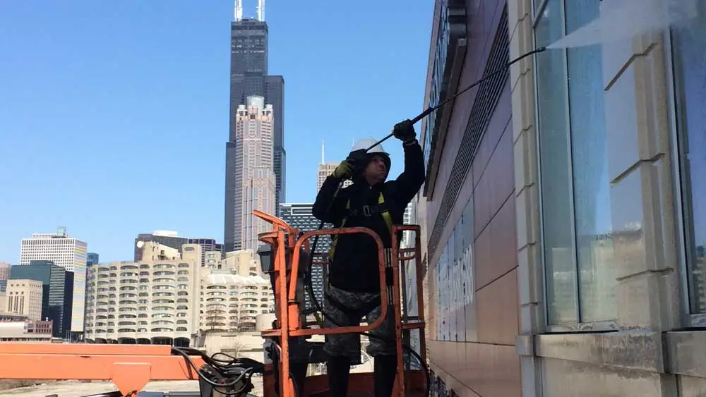 man cleaning a building facade with a power washer